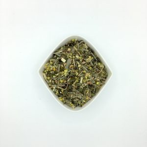 Rautenförmige, weiße Porzellanschale mit gröberen grünlichen Kräuterstücken und gelben Katzenpfötchenblüten