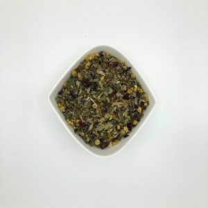 Die weiße rautenförmige Porzellanschale enthält mittelgrüne kleingeschnittene Kräuter, gelbe Kamillen- und dunkelrote Klatschmohnblüten.