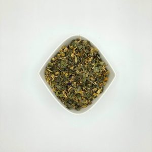 Die weiße rautenförmige Porzellanschale enthält mittelgrüne Blattfragmente und viele gelbe Blüten.