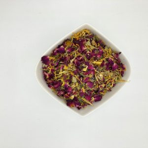 Die weiße rautenförmige Porzellanschale enthält vorwiegend gelbe und magentafarbene Blütenblätter.