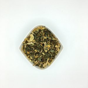 Die weiße rautenförmige Porzellanschale enthält dunkelgrüne, gelbe und schwarzbräunliche Blatt-, Blüten- und Wurzelstücke.